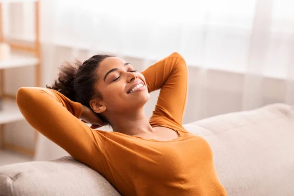 Gelukkig afro meisje ontspannen zitten op bank thuis — Stockfoto