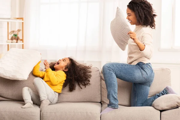 Moeder en dochter vechten met kussens lachen spelen thuis — Stockfoto