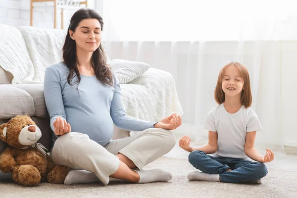 Jovem grávida com pequena filha fazendo exercícios de ioga — Fotografia de Stock