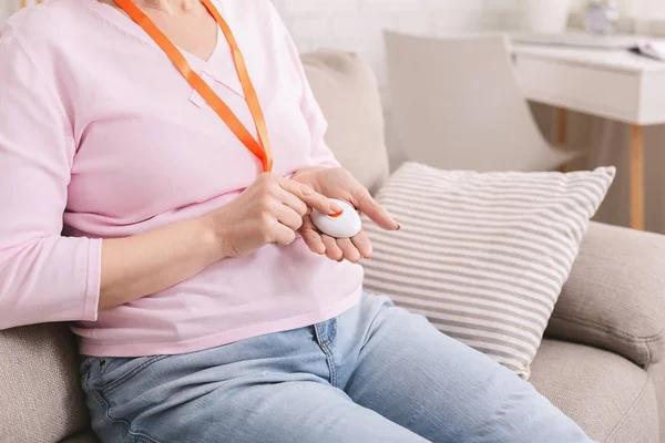 Femme âgée appuyant sur le bouton d'alarme rouge à la maison — Photo