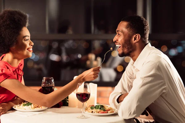 Радостная пара кормит друг друга во время романтического свидания в ресторане — стоковое фото