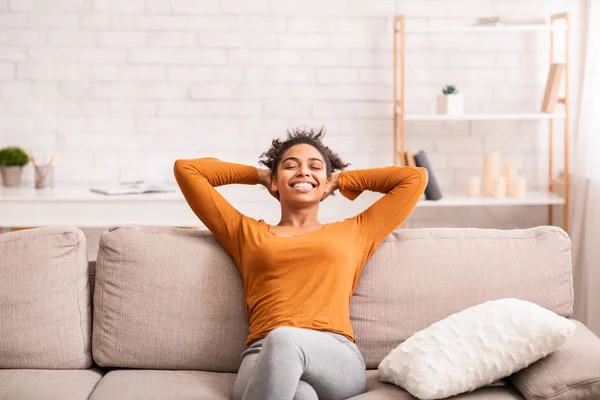 Szczęśliwy czarny kobieta relaks siedzi na kanapie w domu — Zdjęcie stockowe