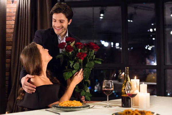 Homem feliz apresentando buquê de rosas para sua amada namorada — Fotografia de Stock