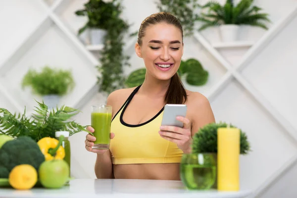 Mulher feliz usando telefone e beber suco de smoothie verde — Fotografia de Stock