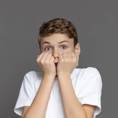 Ellerinin arkasına saklanan korkmuş çocuk, gri stüdyo geçmişi.