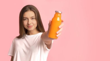 Formda, güzel, genç bir kadın elinde sağlıklı, portakal suyu ya da meyve suyu tutuyor.