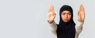 Ciddi Afro İslamcı kız avuçlarını açıp el hareketi yapıyor.