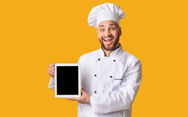 Chef Holding Digital Tablet Pokazuje pusty ekran na stojąco, żółte tło — Zdjęcie stockowe