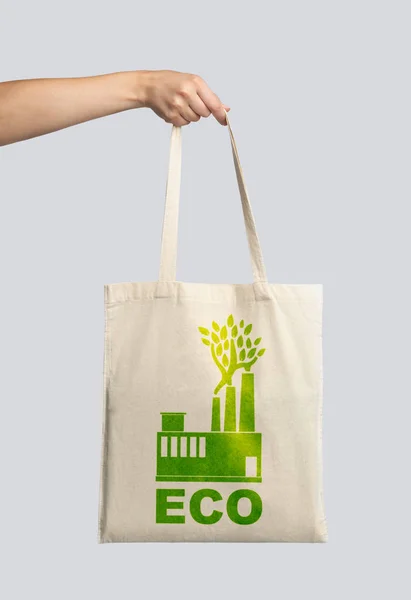 Mão feminina segurando bolsa de lona branca com impressão ecológica verde — Fotografia de Stock