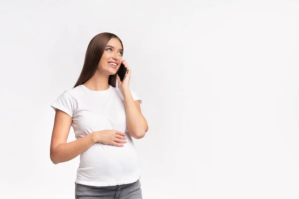 Alegre embarazada chica hablando en teléfono de pie en estudio — Foto de Stock