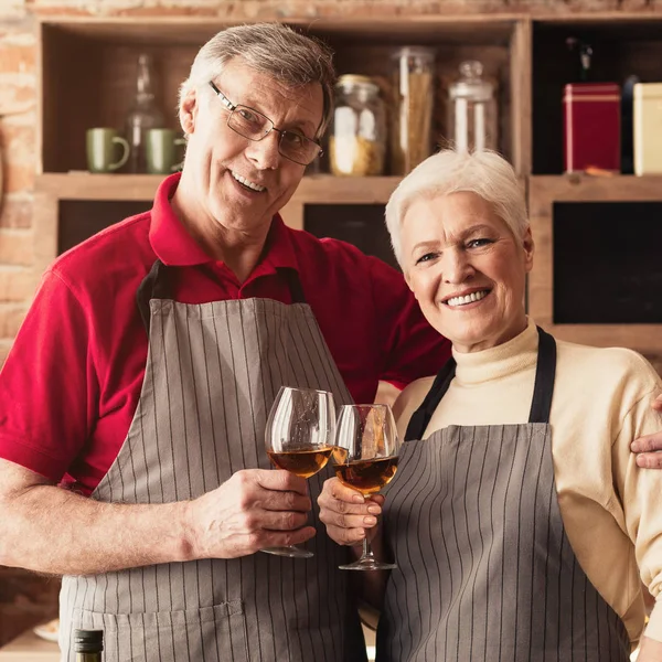Feliz anciano amado hombre y mujer disfrutando del vino en la cocina —  Fotos de Stock