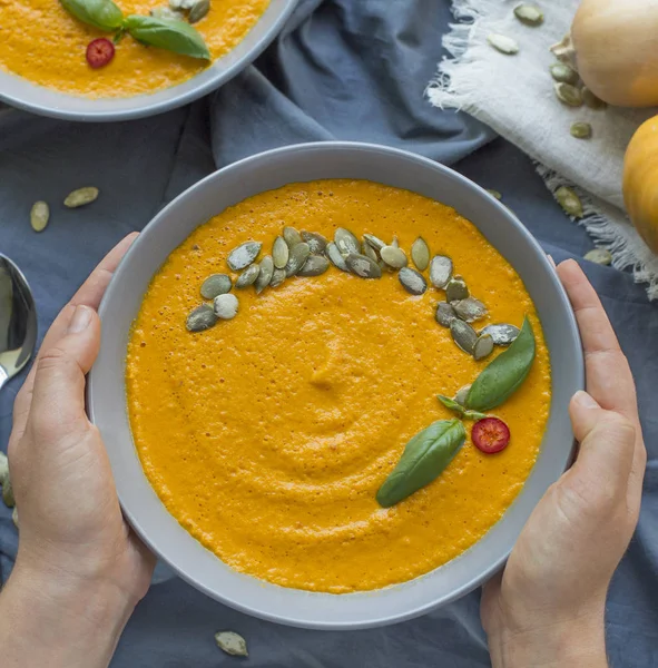 Hands Holding plate with vegan pumpkin cream soup