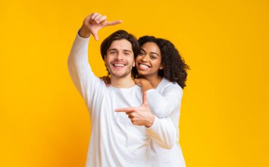 Romantik, ırklar arası bir çift ellerle çerçeve yapıyor ve sarılıyorlar.