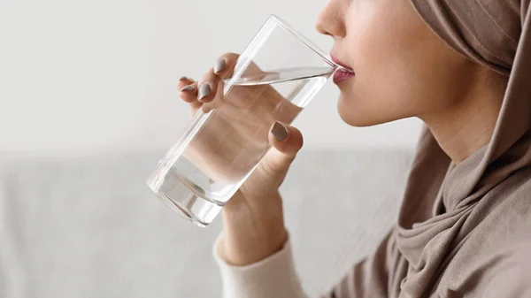 Islamic woman in hijab drinking clear water, holding glass in hand — Stock Photo, Image