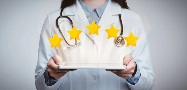 Médico femenino irreconocible sosteniendo la tableta digital con cinco iconos de las estrellas arriba — Foto de Stock