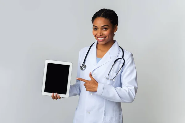 Afro Ärztin zeigt auf digitales Tablet mit leerem Bildschirm — Stockfoto