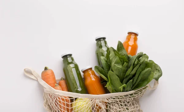 Свежий смузи в стеклянных бутылках и свежие овощи в сетке многоразового использования мешок — стоковое фото