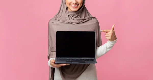 Wanita muslim tak dikenal memegang dan menunjuk laptop dengan layar hitam — Stok Foto