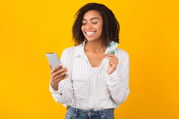 Black woman holding credit card and mobile phone — 스톡 사진