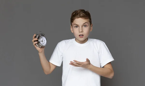 Chocado teen menino segurando despertador na mão — Fotografia de Stock