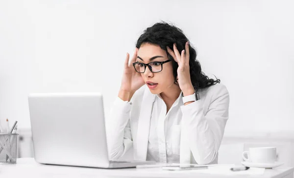 Chocado surpreendido latina mulher usando pc tocando templos — Fotografia de Stock