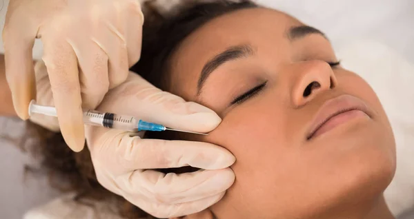 Aesthetic cosmetology. Black woman getting beauty facial injection