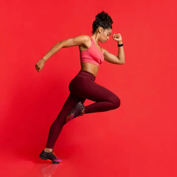 Chica en ropa deportiva corriendo sobre fondo rojo —  Fotos de Stock