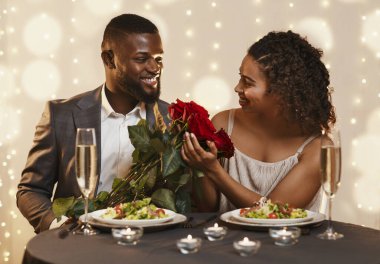 Yakışıklı siyah adam kadınına güzel çiçekler veriyor.