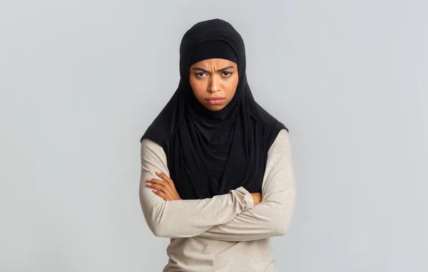 Offended black muslim woman in hijab standing with folded arms over gray background — Stock Photo, Image