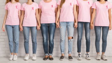 Pembe tişörtlü tanınmayan kadınlar el ele tutuşuyor Duvarın yanında