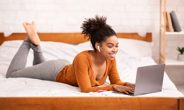 Африканська американська дівчина використовує ноутбук Вивчення онлайн брехня на ліжку — стокове фото