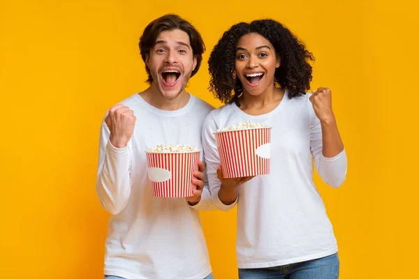 Emocional casal interracial desfrutando de filme com baldes de pipoca — Fotografia de Stock