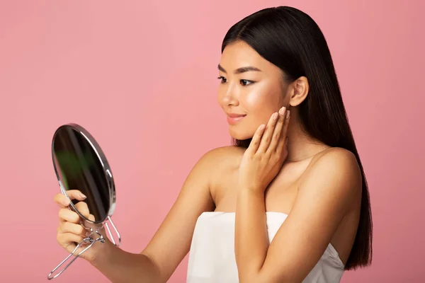 Personlig vård. Asiatisk flicka håller spegel och beundrar sig själv — Stockfoto