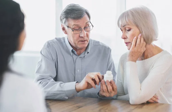 Ältere Paare fragen ihren Arzt nach ihrer Behandlung — Stockfoto