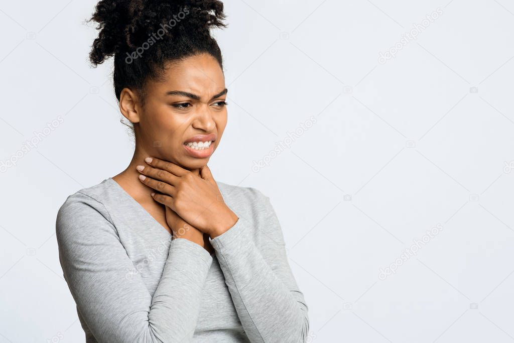 Afro girl suffering from sore throat, touching her neck