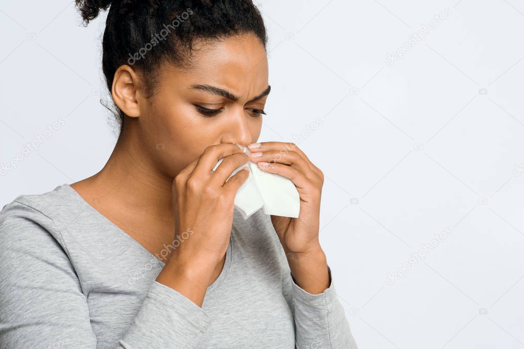 Woman wiping her nose with napkin, having flue