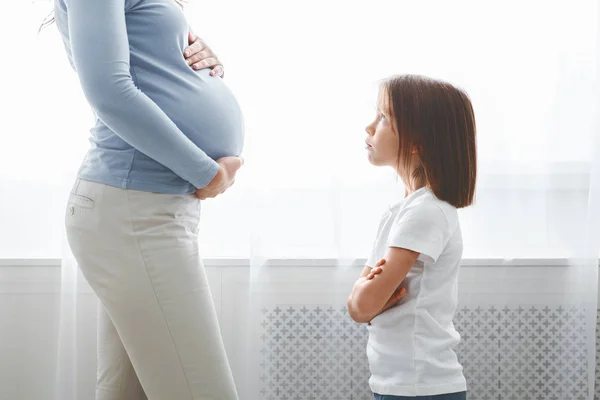 Little girl looking at her expecting mom with reproach — 스톡 사진