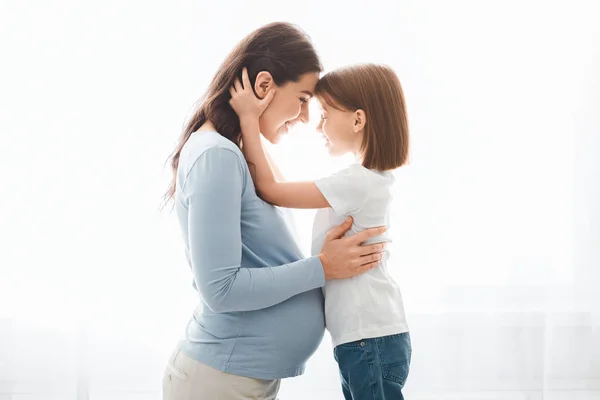 Amare piccola figlia abbracciando la sua madre in attesa — Foto Stock