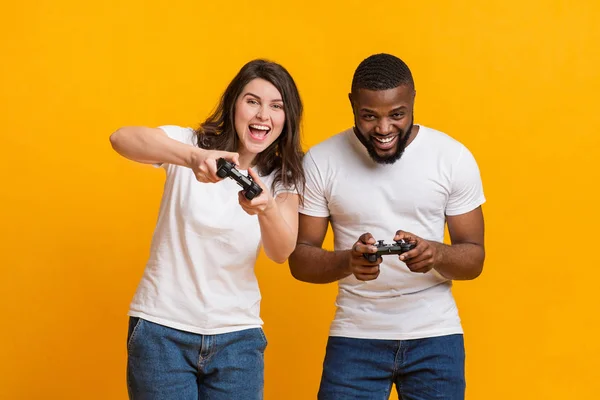 Joyful interracial casal segurando joysticks competindo uns aos outros em jogos de vídeo — Fotografia de Stock