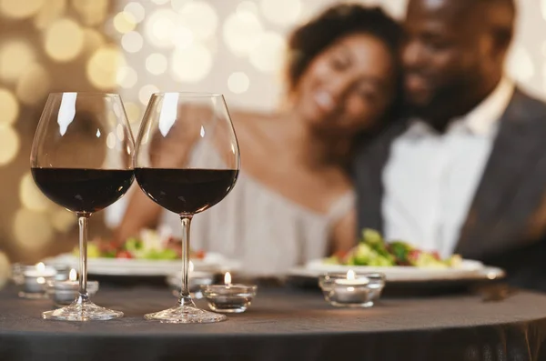 Selective focus on two glasses of wine over cuddling couple — 스톡 사진