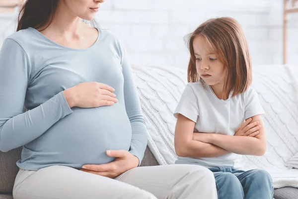 Upset little girl looking at her pregnant mother belly — 스톡 사진
