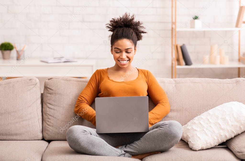 Afro Woman Working On Laptop Sitting On Couch At Home