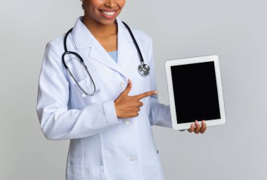 Tanımlanamayan siyah doktor siyah ekranlı dijital tableti işaret ediyor.