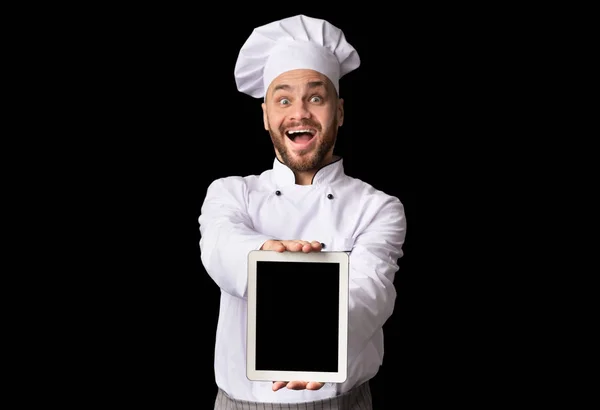 Kuchař zobrazování tablet s prázdným displejem pózu na černém pozadí — Stock fotografie