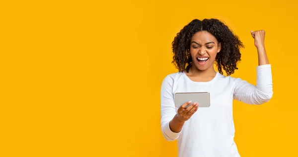 Juegos de azar afro chica jugando videojuego en el teléfono inteligente, celebrando la victoria — Foto de Stock