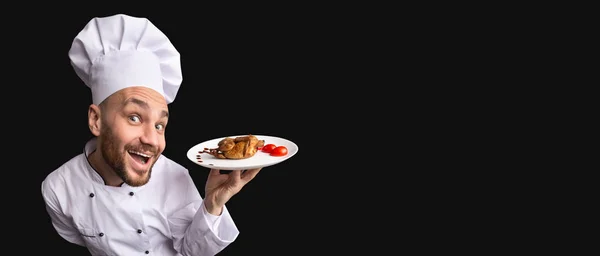 Chef emocionado sosteniendo plato de pollo de pie sobre fondo negro, Panorama —  Fotos de Stock