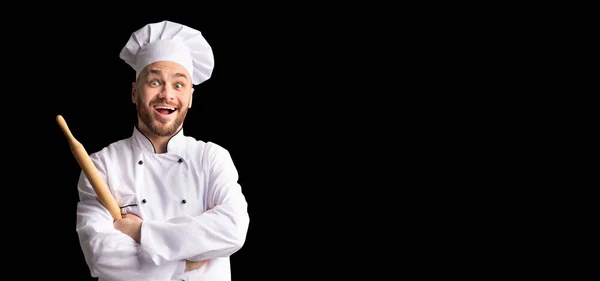 Baker excité posant avec la goupille de roulement de la pâte sur fond noir — Photo