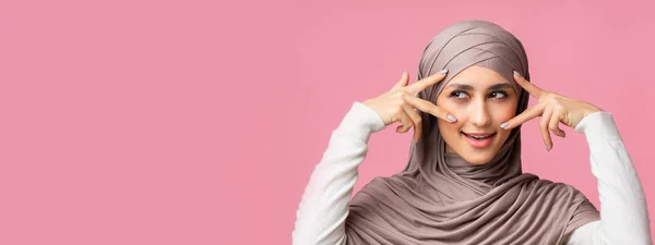 Schöne orientalische Frau im Hijab, die Finger in Augennähe hält und V-Zeichen zeigt — Stockfoto