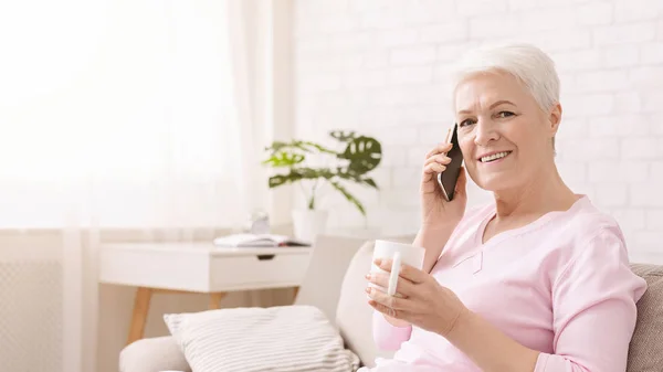 Pozytywna starsza kobieta rozmawiająca przez telefon w domu — Zdjęcie stockowe