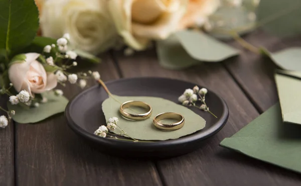 Par de anillos de boda dorados y rosas en madera —  Fotos de Stock